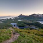 Hiker on top of Tjeldbergtinden enjoying the view over Kabelvåg with Vågakallen mountain in the background.