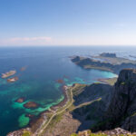 Panoramic view from the top of Nordlandsnupen on Værøy, showing Sørland and surrounding turquoise waters.