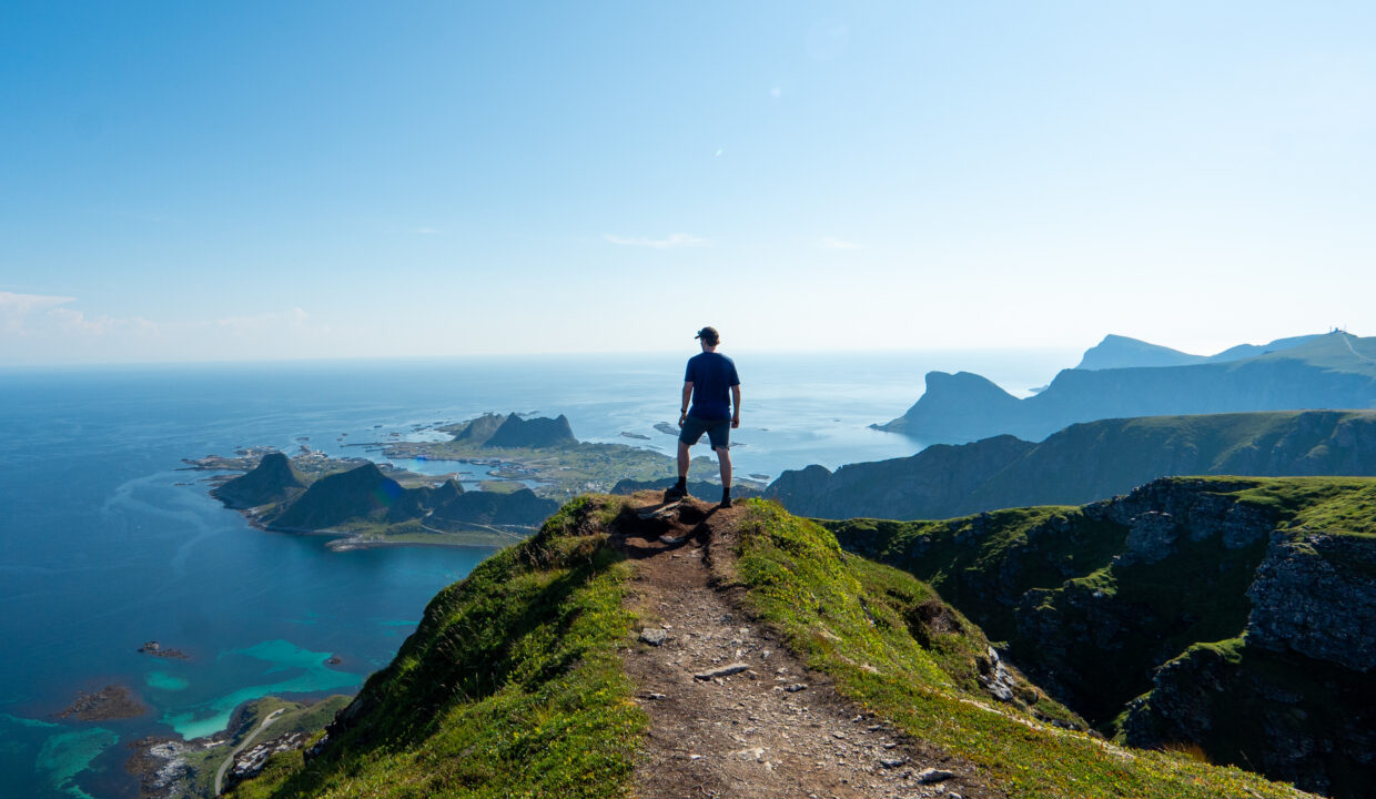 Hiker on Nordlandsnupen Summit with Stunning View of Værøy