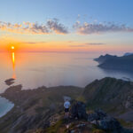 Sunset view from Moltinden with hiker standing above Rambergstranda and the sea glowing orange.